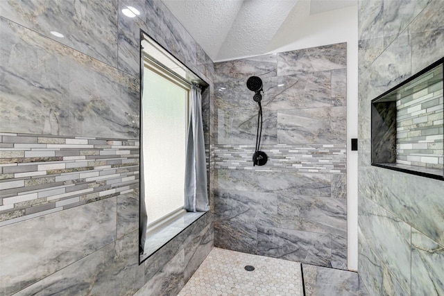 bathroom featuring a textured ceiling and tiled shower