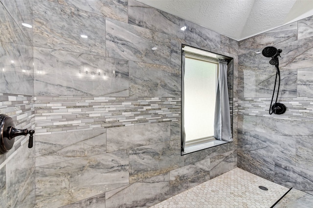 bathroom with a tile shower and a textured ceiling