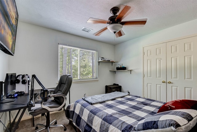 carpeted bedroom with ceiling fan, a closet, and a textured ceiling