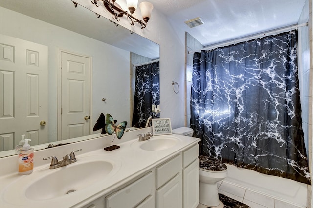 bathroom with tile patterned floors, vanity, toilet, and a textured ceiling