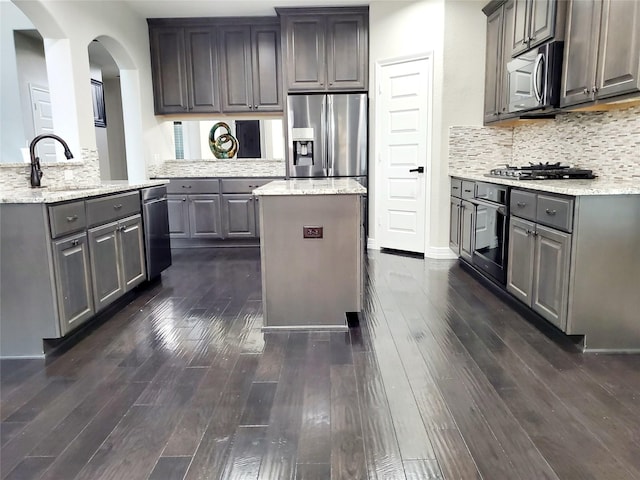 kitchen with gray cabinetry, stainless steel appliances, sink, dark hardwood / wood-style floors, and a kitchen island