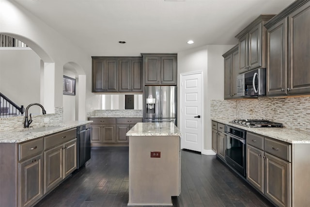 kitchen featuring sink, dark hardwood / wood-style floors, kitchen peninsula, a kitchen island, and appliances with stainless steel finishes