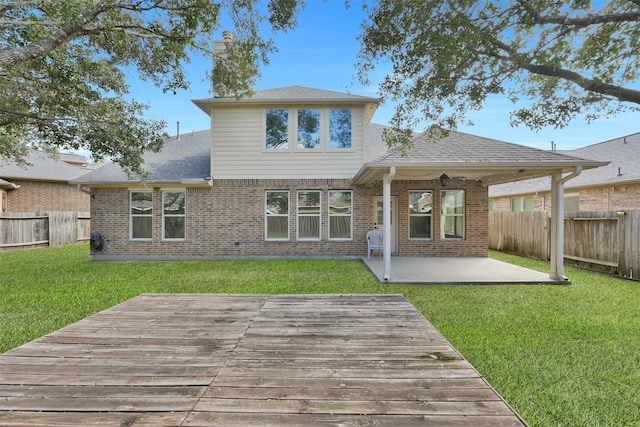 back of house featuring a deck, a patio area, and a lawn