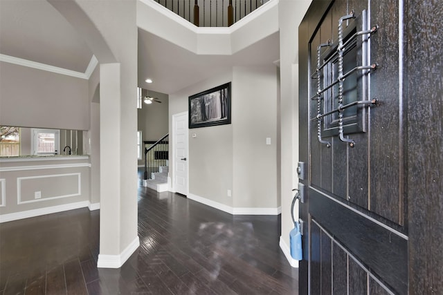 entrance foyer featuring crown molding, a towering ceiling, dark hardwood / wood-style floors, and ceiling fan