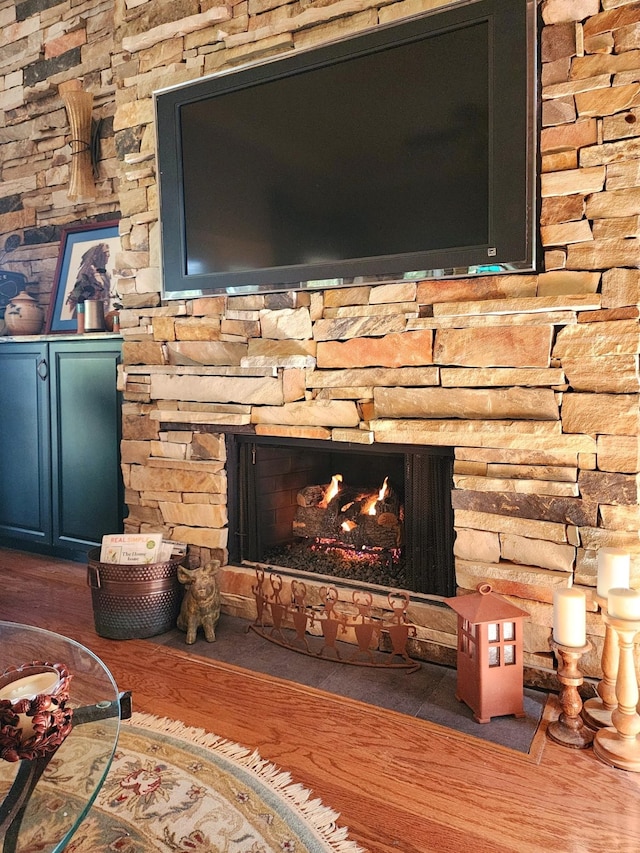 interior details featuring a stone fireplace and wood finished floors