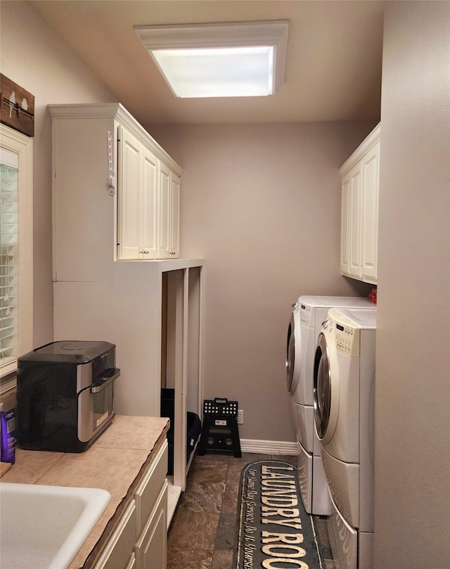 clothes washing area with baseboards, separate washer and dryer, and cabinet space