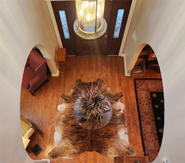 entrance foyer featuring a chandelier, wood finished floors, baseboards, and arched walkways