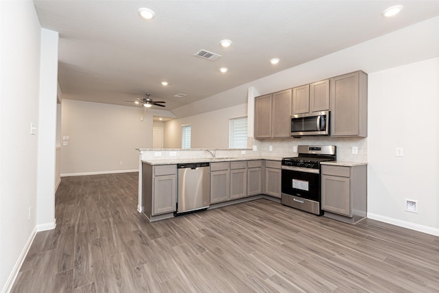 kitchen with ceiling fan, wood-type flooring, kitchen peninsula, and stainless steel appliances