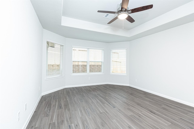 spare room with ceiling fan, a raised ceiling, and wood-type flooring