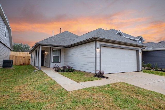 view of front of house featuring a garage, cooling unit, and a lawn