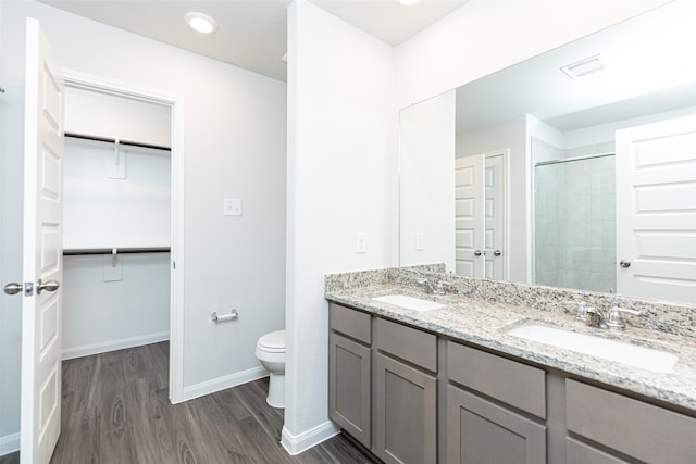 bathroom with tiled shower, vanity, hardwood / wood-style flooring, and toilet