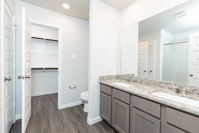 bathroom with vanity, toilet, wood-type flooring, and tiled shower