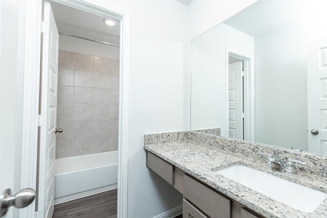 bathroom featuring vanity, wood-type flooring, and tiled shower / bath