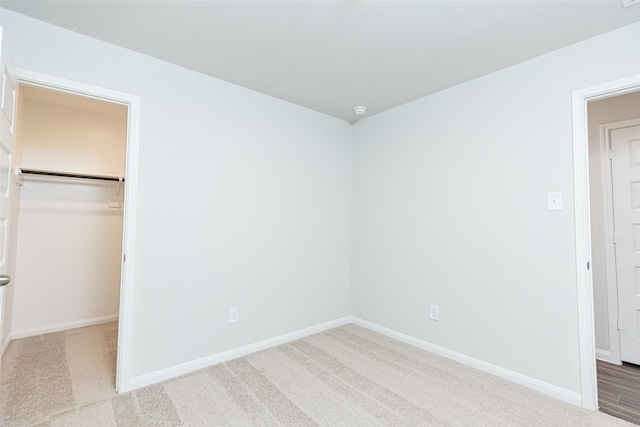 unfurnished bedroom with a walk in closet, light carpet, and a closet