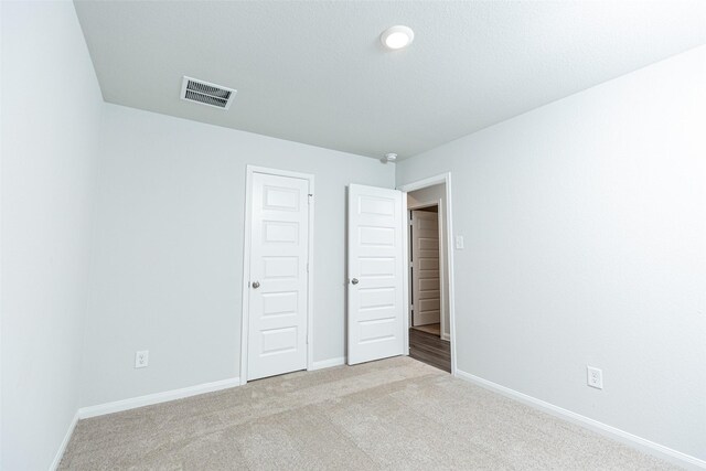 unfurnished bedroom featuring light carpet and a closet