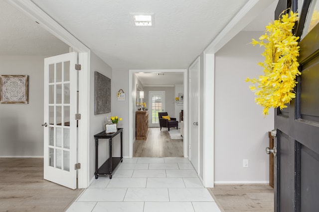 hall featuring crown molding, light hardwood / wood-style floors, and a textured ceiling