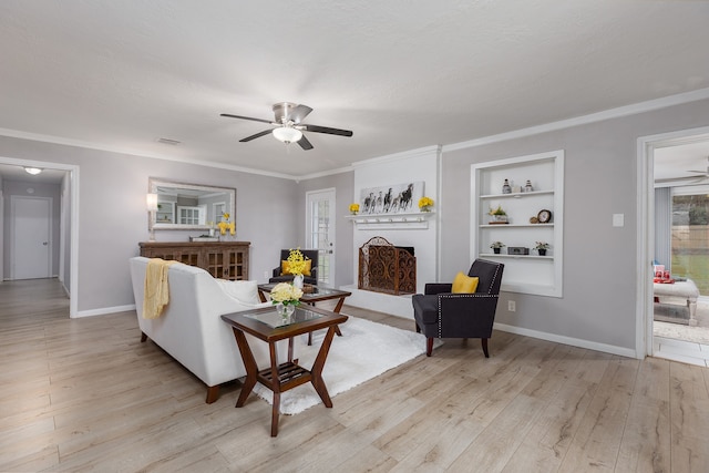 living room featuring built in shelves, ceiling fan, light wood-type flooring, and ornamental molding