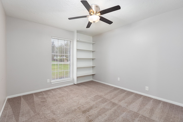 carpeted spare room featuring ceiling fan and a textured ceiling