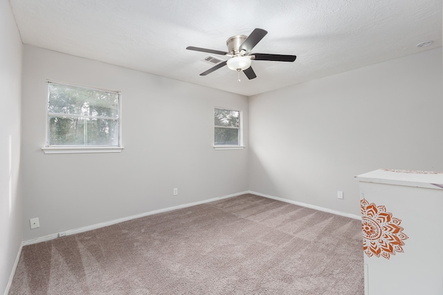 carpeted spare room with ceiling fan and a textured ceiling