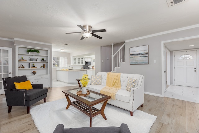 living room featuring a textured ceiling, light hardwood / wood-style floors, built in features, and ceiling fan