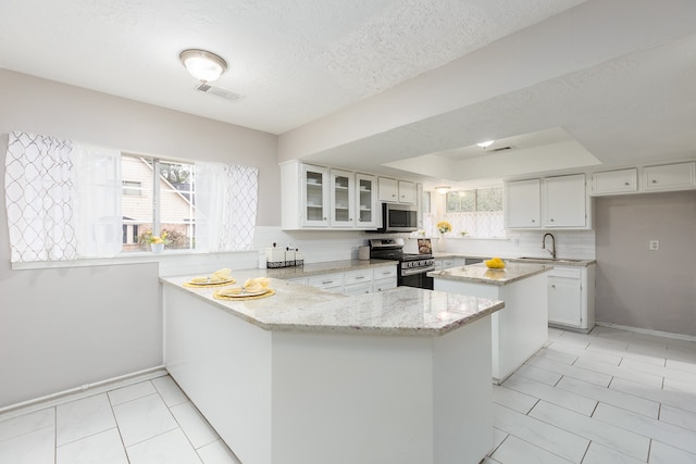 kitchen with backsplash, white cabinets, light stone countertops, appliances with stainless steel finishes, and kitchen peninsula