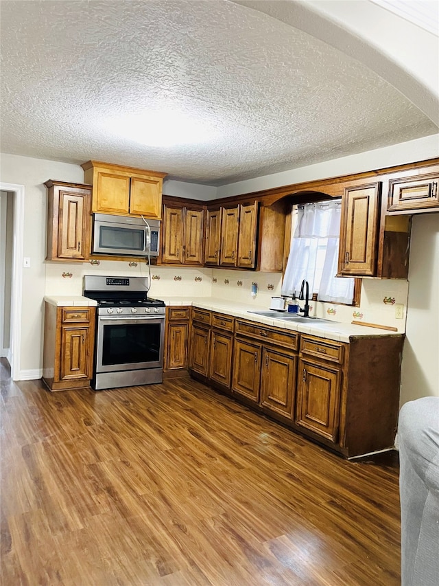 kitchen with a textured ceiling, dark hardwood / wood-style floors, sink, and stainless steel appliances