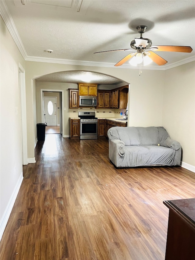 unfurnished living room featuring dark wood-type flooring, crown molding, sink, ceiling fan, and a textured ceiling