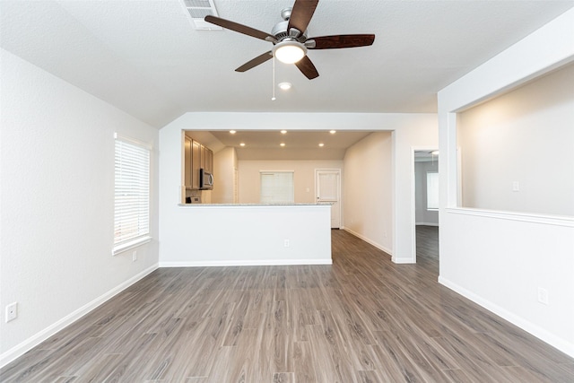 unfurnished living room featuring hardwood / wood-style floors, ceiling fan, a textured ceiling, and vaulted ceiling