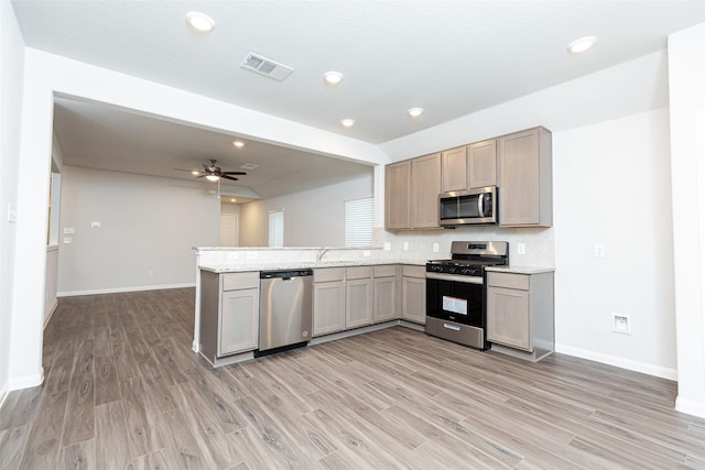 kitchen featuring kitchen peninsula, appliances with stainless steel finishes, backsplash, light wood-type flooring, and ceiling fan