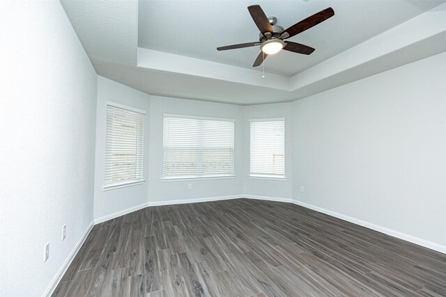 spare room featuring ceiling fan, a raised ceiling, and dark wood-type flooring