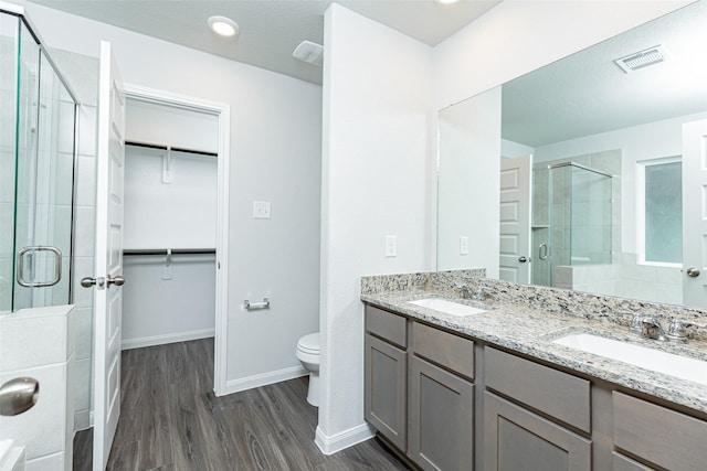 bathroom with hardwood / wood-style floors, vanity, a shower with shower door, and toilet