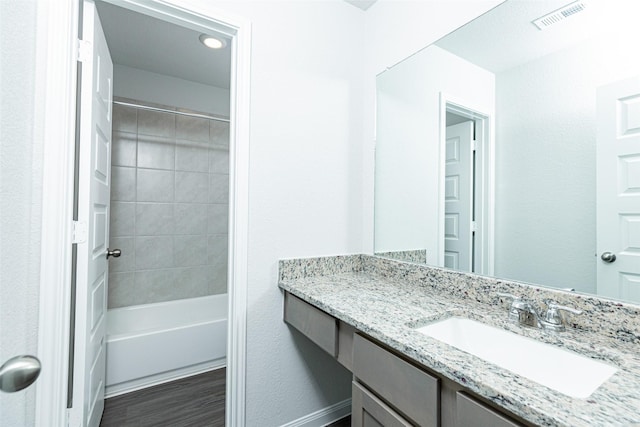 bathroom featuring vanity, hardwood / wood-style flooring, and tiled shower / bath