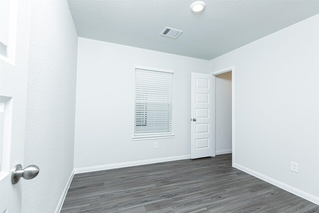 spare room with a textured ceiling and dark hardwood / wood-style floors