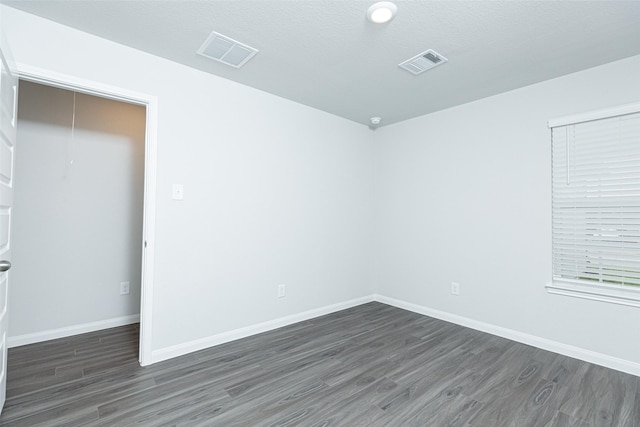 empty room featuring a textured ceiling and dark hardwood / wood-style flooring