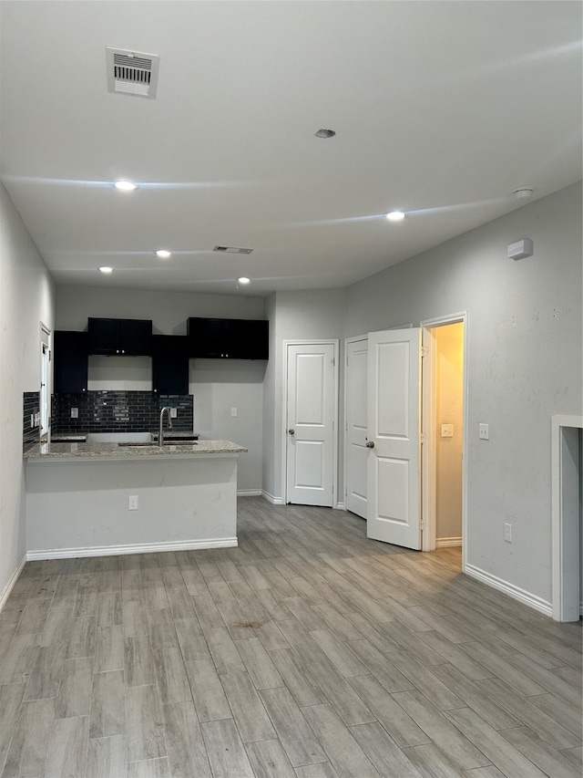 kitchen featuring kitchen peninsula, decorative backsplash, ventilation hood, sink, and hardwood / wood-style floors