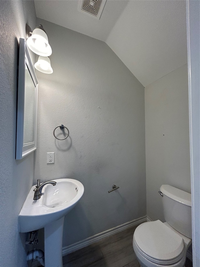 bathroom with hardwood / wood-style floors, toilet, and lofted ceiling