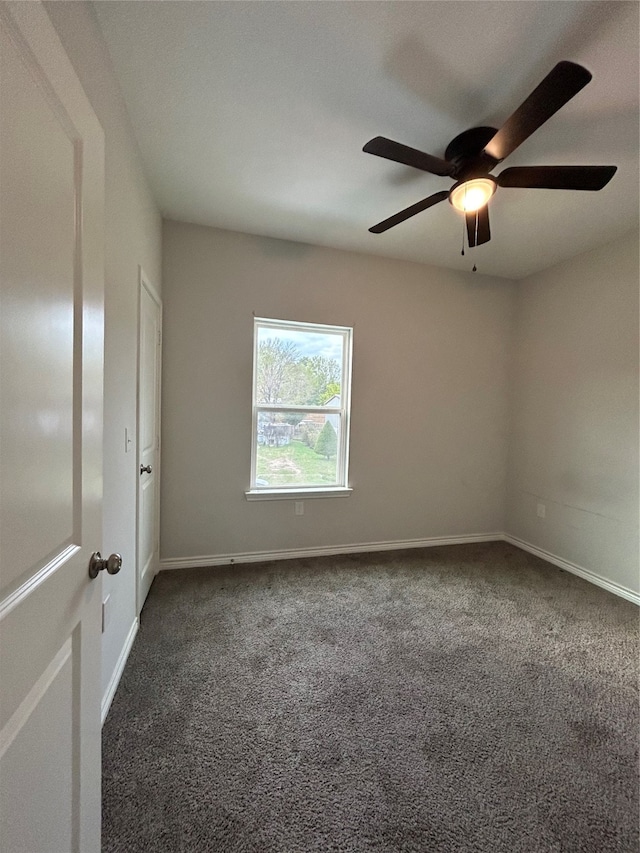 spare room with dark colored carpet and ceiling fan