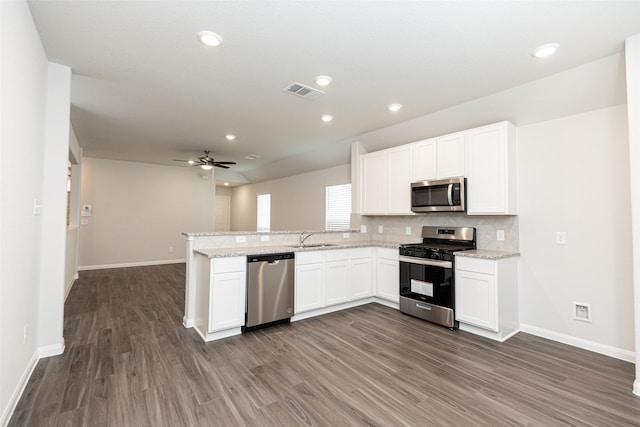 kitchen featuring kitchen peninsula, light stone counters, stainless steel appliances, sink, and white cabinets