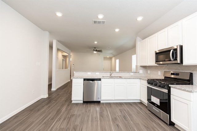 kitchen featuring white cabinets, stainless steel appliances, light stone countertops, and sink