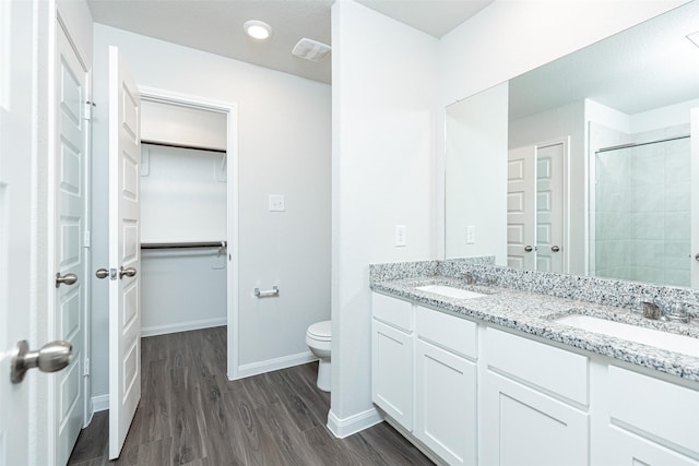 bathroom featuring a tile shower, vanity, hardwood / wood-style flooring, and toilet