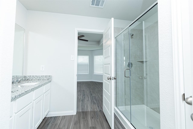 bathroom featuring vanity, hardwood / wood-style flooring, an enclosed shower, and ceiling fan