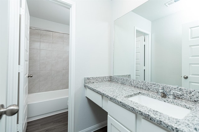 bathroom with vanity, wood-type flooring, and tiled shower / bath