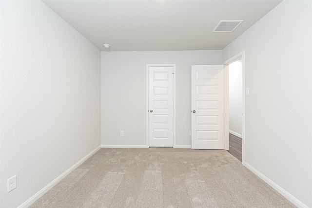 unfurnished bedroom featuring light carpet and a closet