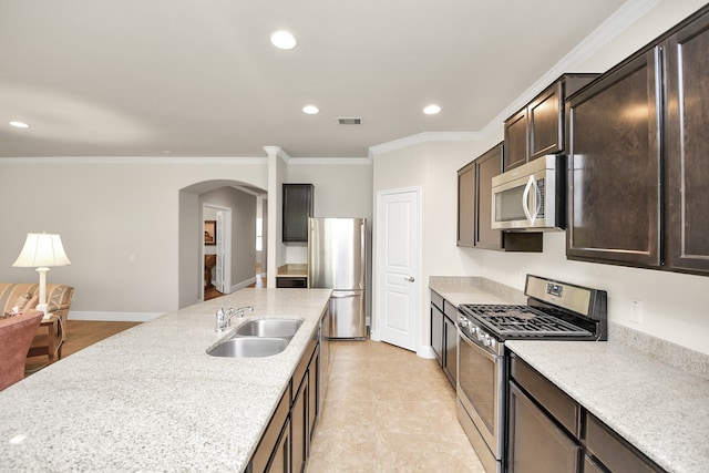 kitchen with sink, ornamental molding, dark brown cabinets, light stone counters, and stainless steel appliances