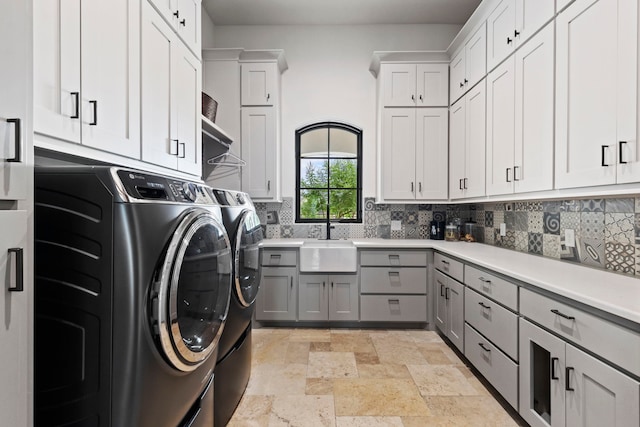 laundry area featuring cabinets, washer and clothes dryer, and sink