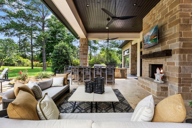 view of patio / terrace featuring ceiling fan, an outdoor living space with a fireplace, and an outdoor bar