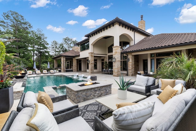 view of pool featuring pool water feature, an outdoor living space with a fire pit, and a patio area