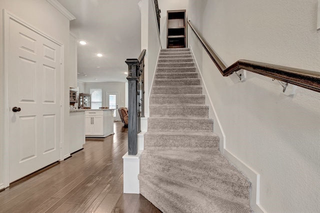 stairs featuring hardwood / wood-style flooring and crown molding