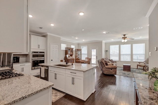 kitchen featuring dark wood-type flooring, stainless steel appliances, light stone counters, a kitchen island with sink, and white cabinets