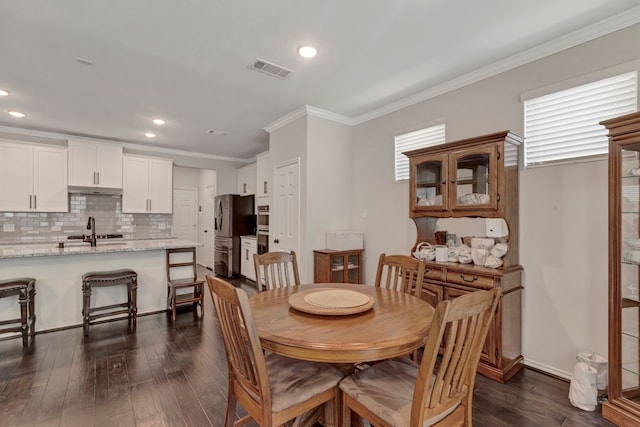 dining area featuring sink, crown molding, and dark wood-type flooring